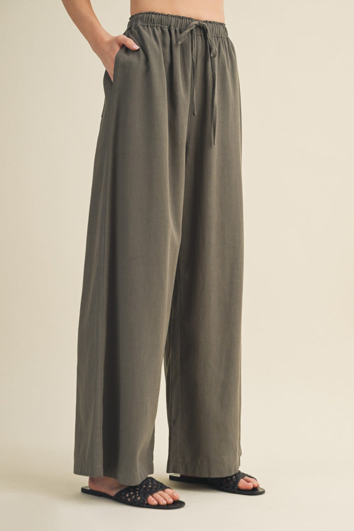 Person wearing olive green wide-leg pants on a beige background
