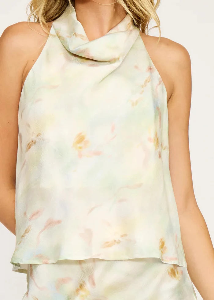 Cream tie-dye sleeveless top with draped cowl neckline and soft watercolor stains in pink, yellow, and green.