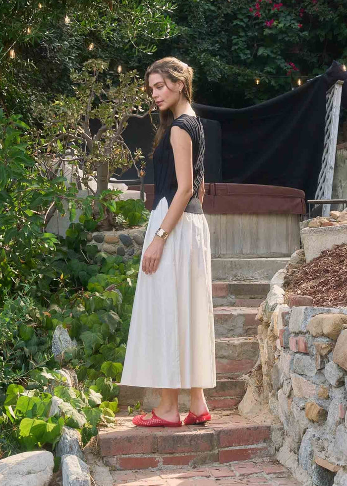 Black and cream sleeveless midi dress with color-block design worn with red flats.