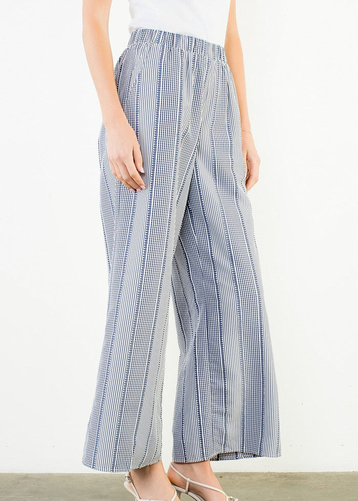 Person wearing blue and white checkered pants on a plain background