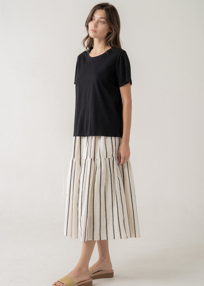 Black short-sleeve t-shirt with crew neckline styled with a striped pleated skirt.