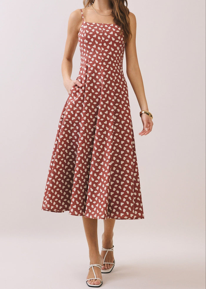 Woman wearing a BROWN and white patterned dress on a plain background
