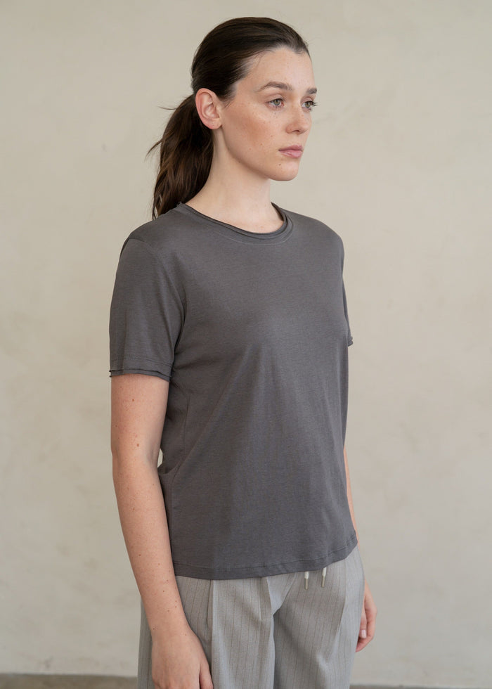 Charcoal gray crew neck t-shirt with short sleeves, displayed on a model in profile view.