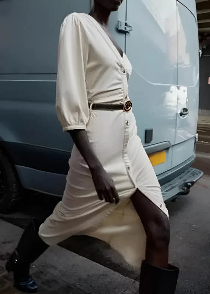 Cream button-front midi dress with puff sleeves and belted waist, worn with black boots.