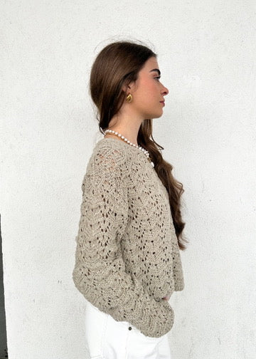 Woman wearing a beige knit sweater with chevron texture pattern, side profile view.