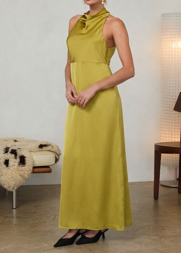 Woman wearing a yellow-green sleeveless halter maxi dress with a draped neckline, paired with black pointed-toe heels.