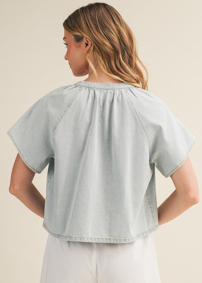 Light wash denim top with v-neck, short puffed sleeves, and gathered neckline.
