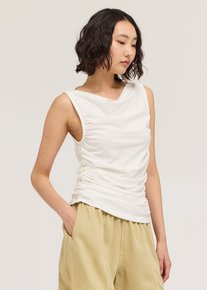 Woman wearing a white sleeveless top and beige shorts on a white background