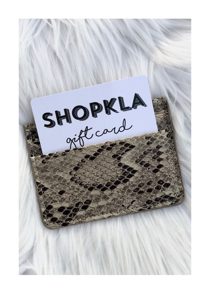 SHOPKLA gift card in white envelope with snakeskin pattern, displayed on white fur background.