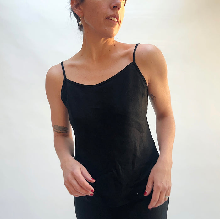 Woman wearing a black tank top against a plain background