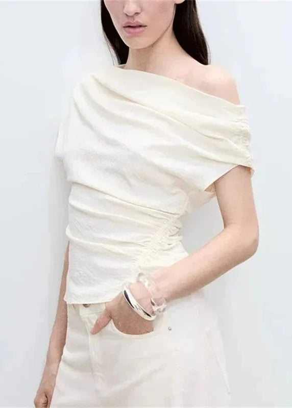 Cream one-shoulder top with draped fabric and ruched side detailing.