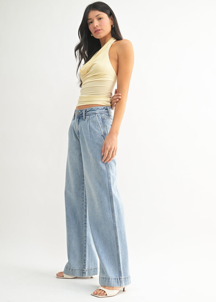 Woman wearing light blue relaxed-fit jeans with a cream wrap-style tank top.