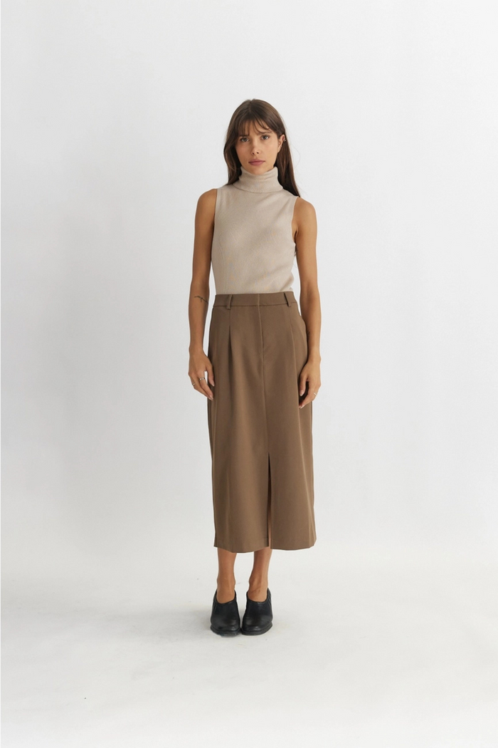 Taupe midi skirt with front slit, styled with cream sleeveless turtleneck and black platform boots.
