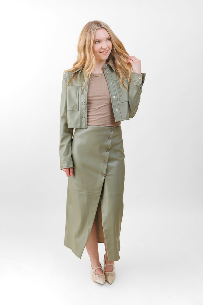 Sage green faux leather midi skirt with button front closure and front slit, styled with matching jacket.