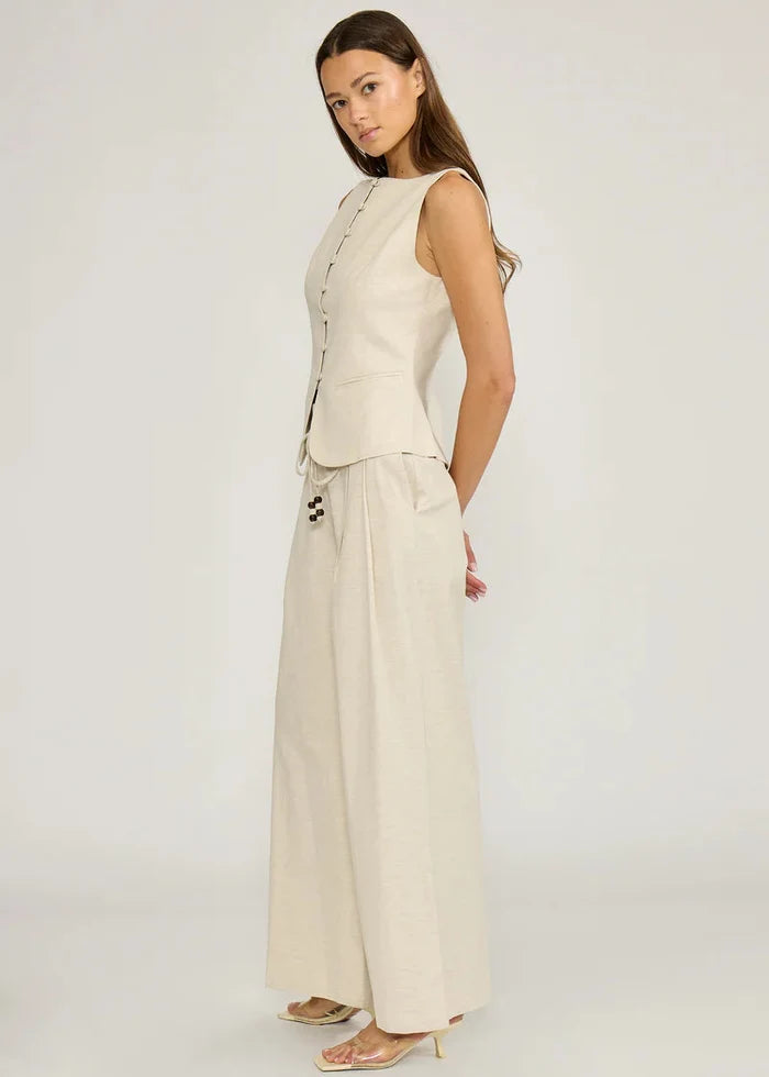 Cream sleeveless vest top with button front closure, shown with matching wide-leg trousers.