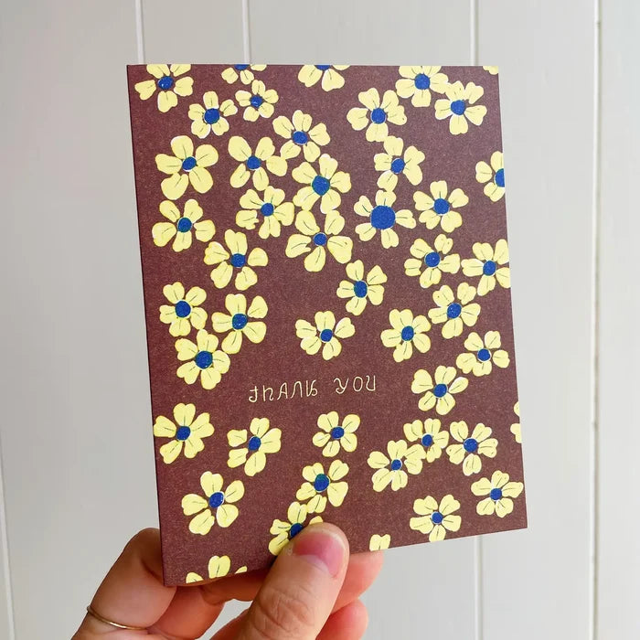 Card with yellow flowers and 'THANK YOU' text held against a white background