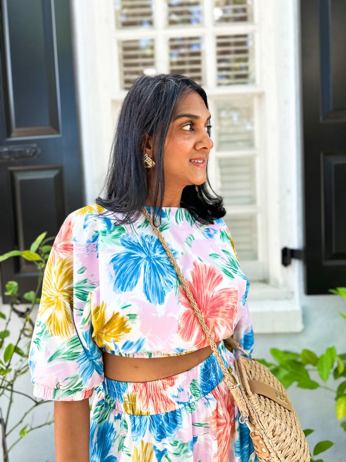 Cropped white top with multicolored floral print in blue, yellow, pink, and green tones.