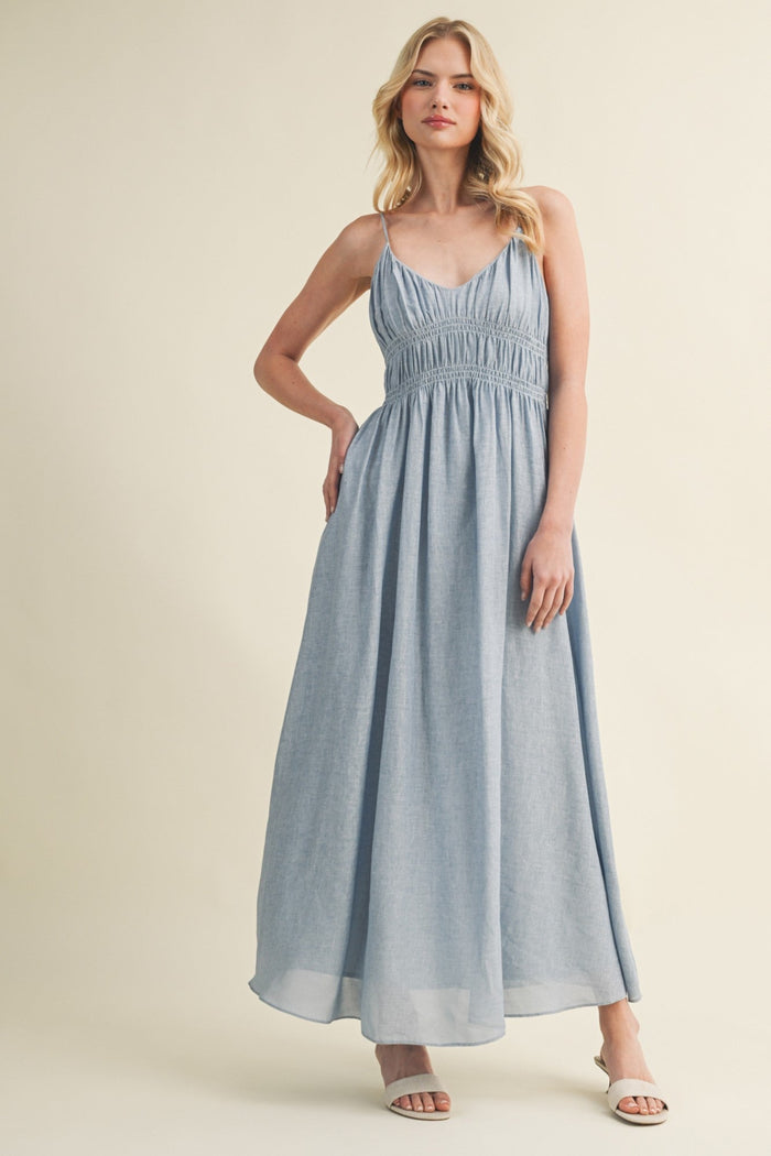 Gray sleeveless maxi dress with V-neckline, thin shoulder straps, and ruched waistband detail.