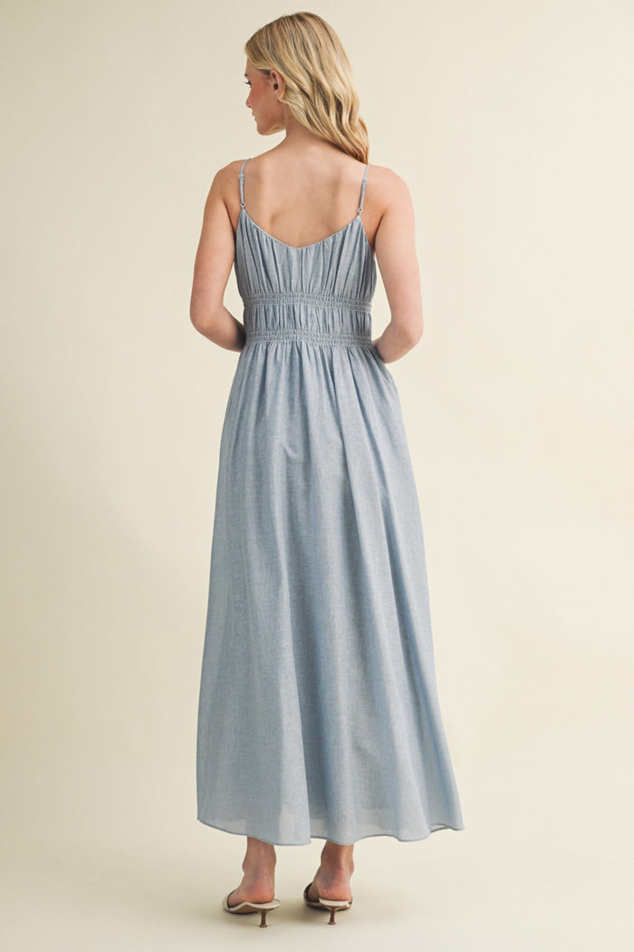 Light blue sleeveless maxi dress with thin straps and gathered waist, shown from the back on a model.
