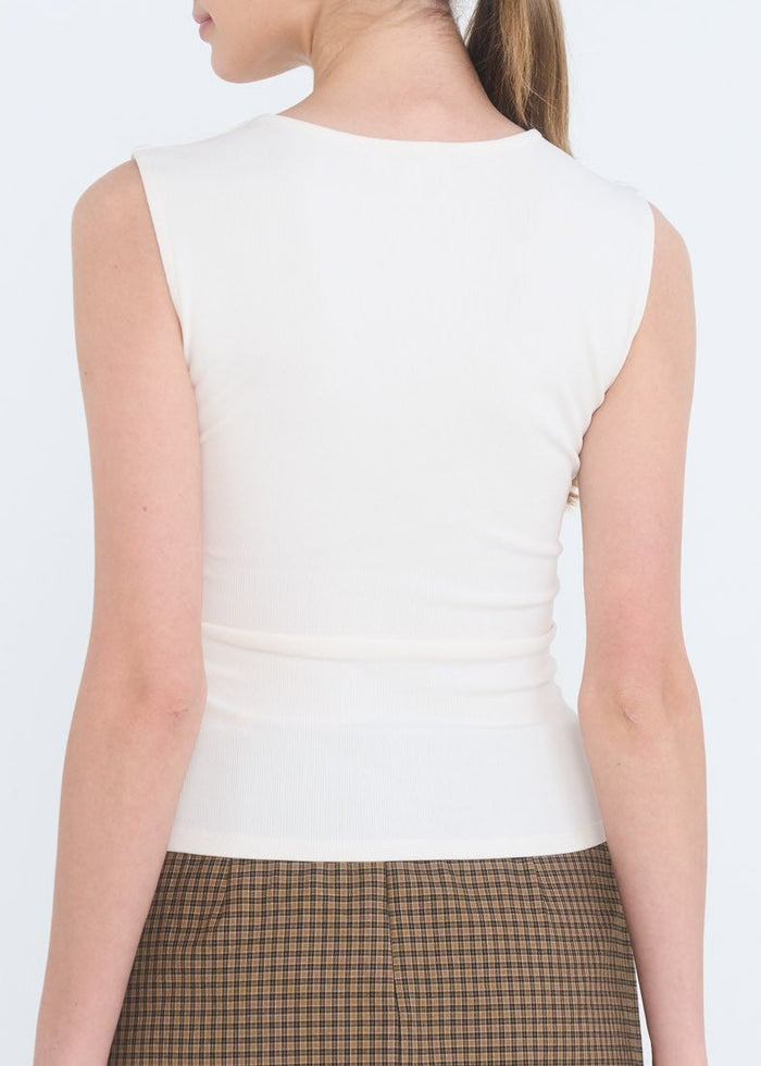 Woman wearing a white sleeveless top and plaid skirt on a white background