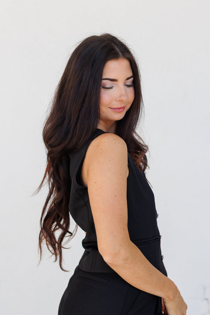 Black sleeveless suit vest with notch lapels, worn by a woman shown from side profile.