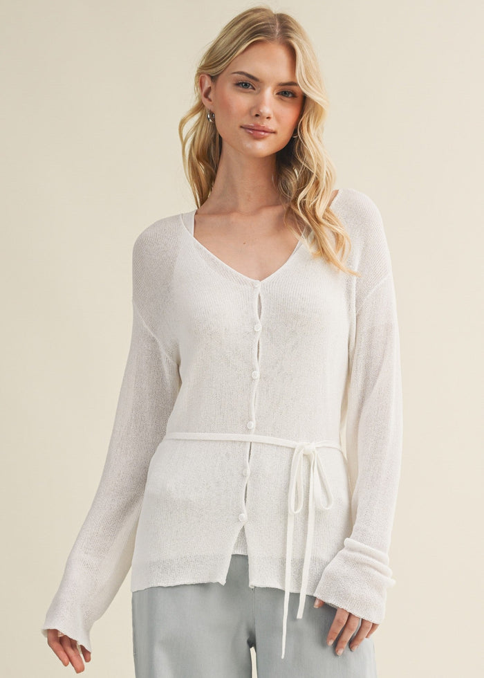 Cream knit cardigan with V-neckline, button front, and drawstring waist tie.