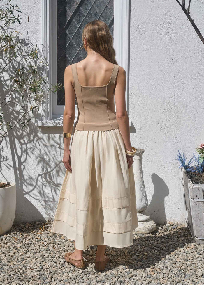 Woman wearing a sleeveless khaki and cream midi dress with a fitted bodice and tiered skirt, shown from back view.