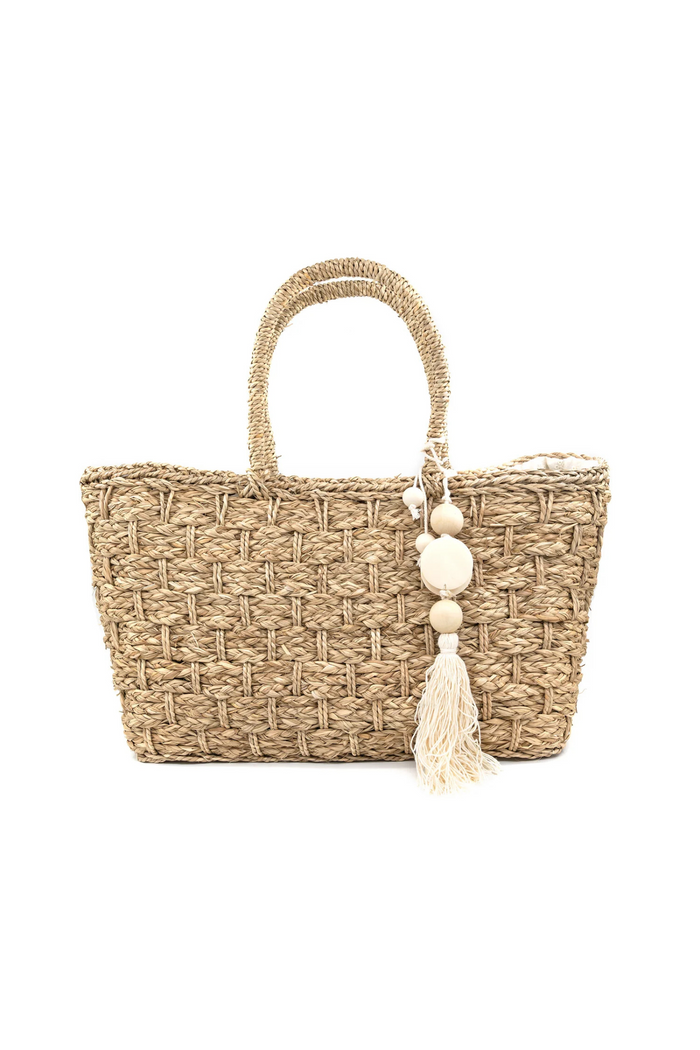 Woven straw tote bag with wrapped handles and cream beaded tassel charm.