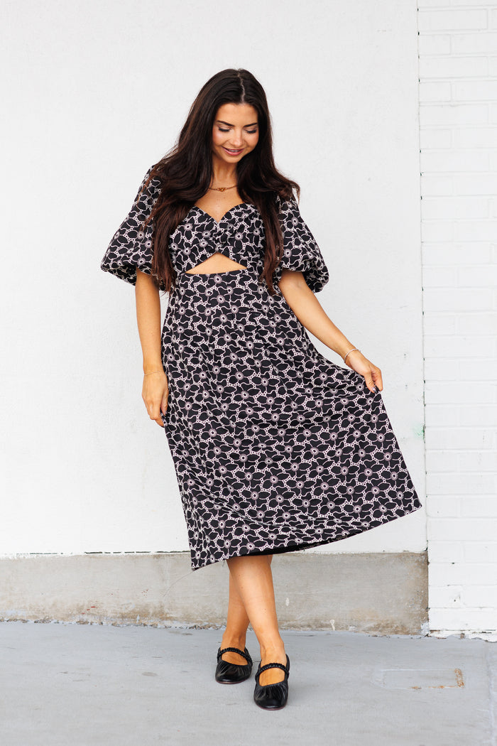 Black and white abstract patterned midi dress with puff sleeves and cutout front detail.