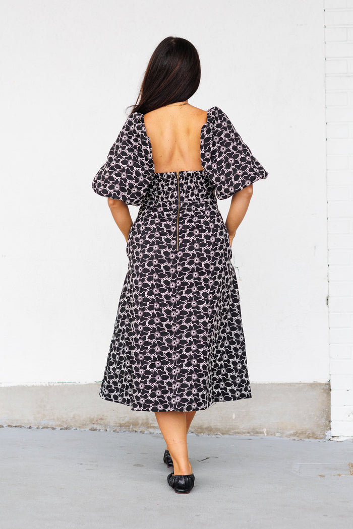 Black and white patterned midi dress with puff sleeves and open back, shown from behind on model.