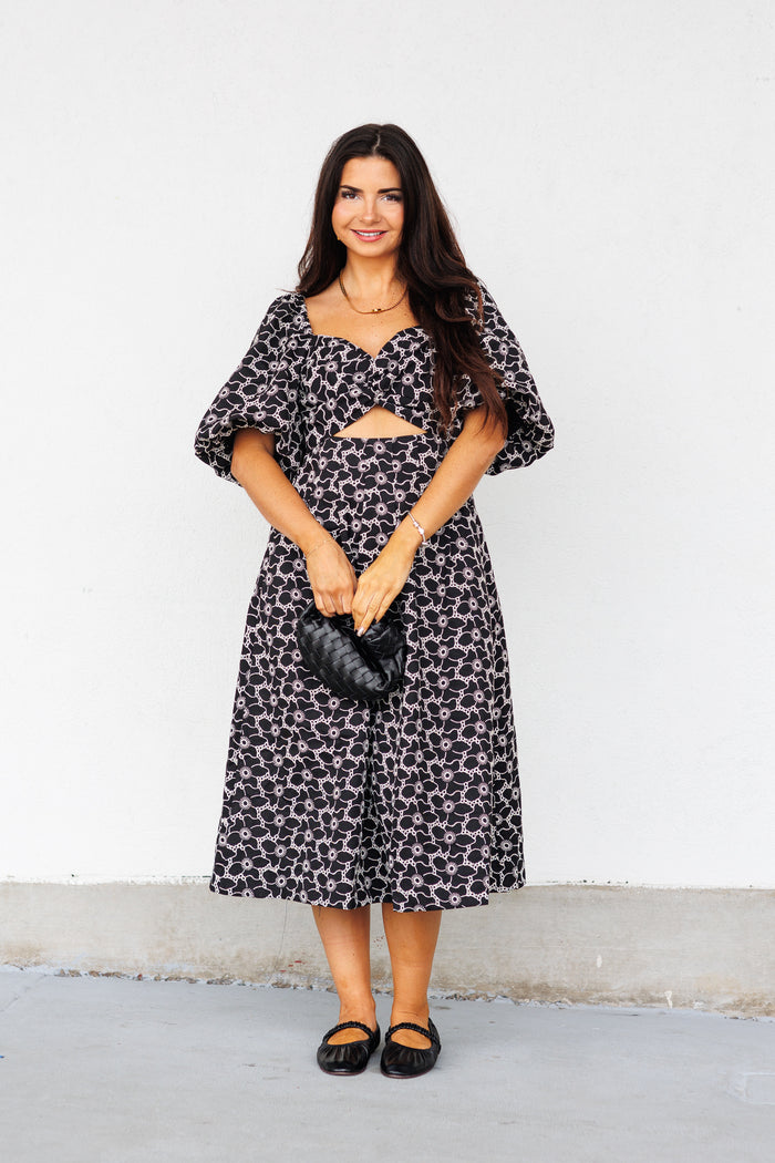 Black and white patterned midi dress with short puffed sleeves and cutout detail at neckline.