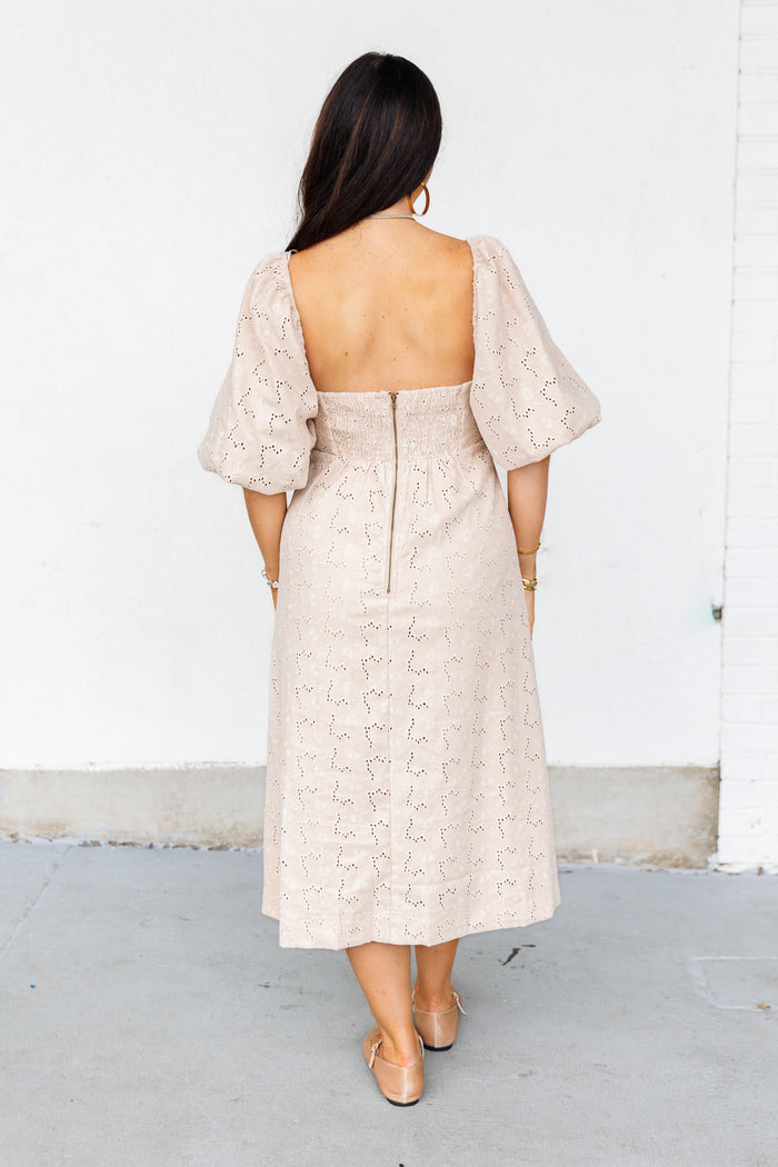 Beige eyelet midi dress with puff sleeves, open back, and zip closure, shown from rear view.