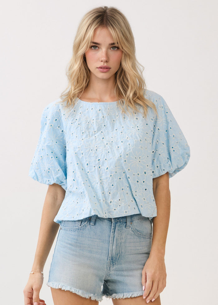 Light blue eyelet top with puffed half sleeves and crew neckline, paired with light wash denim shorts.