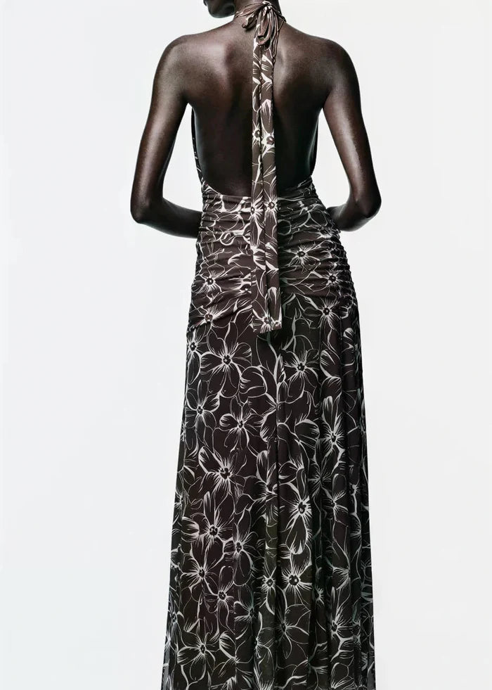 Black halter maxi dress with white floral print, shown from back with tie closure at neck.