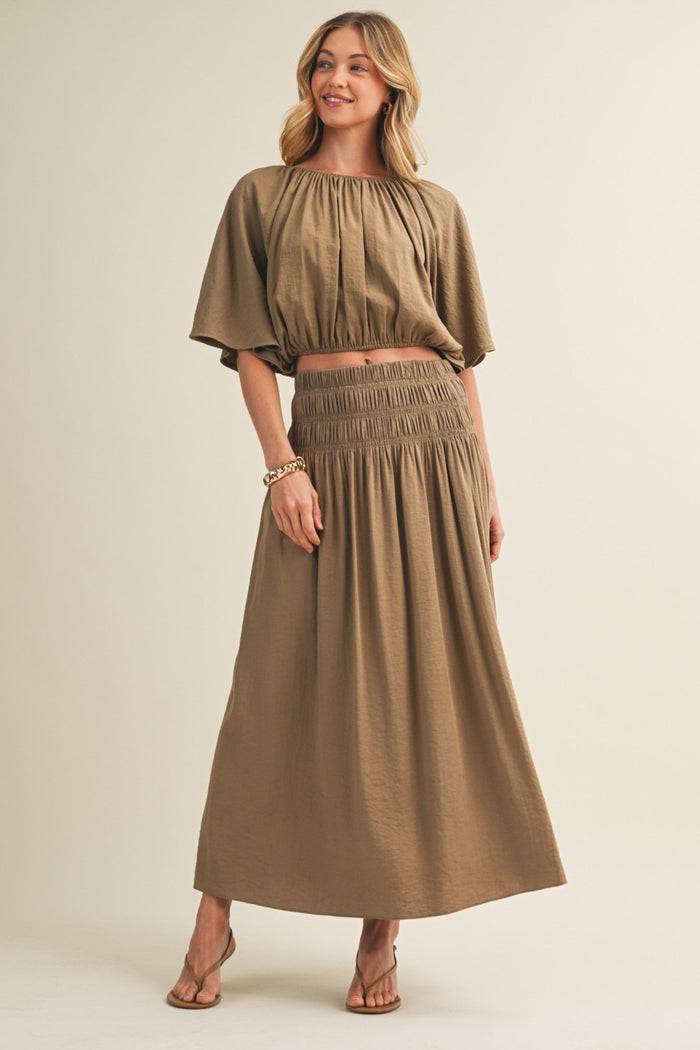 Tan a-line maxi skirt with smocked waistband, worn with matching cropped top.