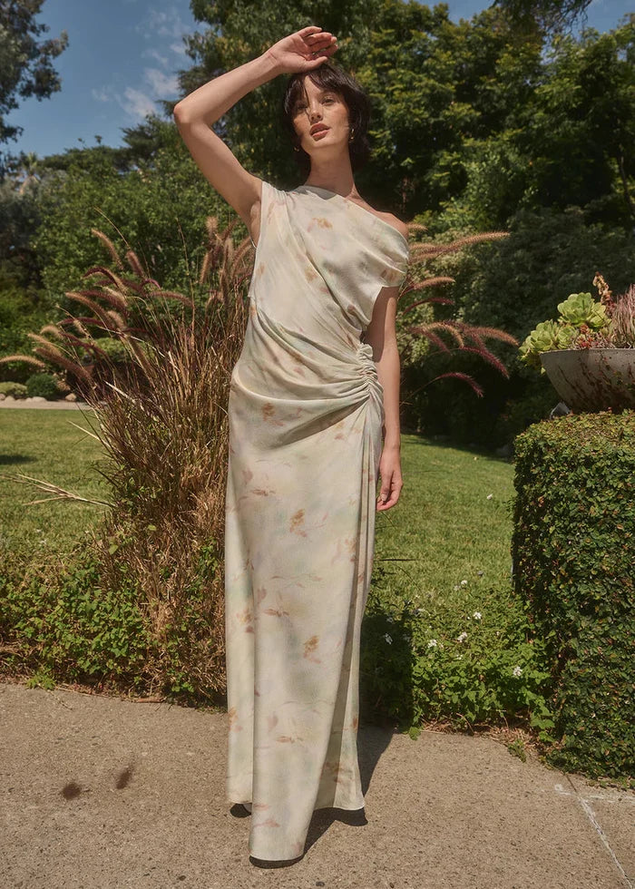 Woman wearing cream tie-dye maxi dress with gathered side ruching and short sleeves, standing in garden setting.