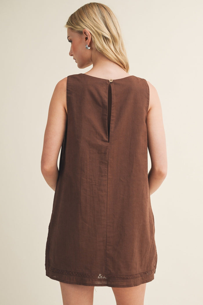 Brown sleeveless shift dress with lace trim at hem, back button closure, and center seam detail.