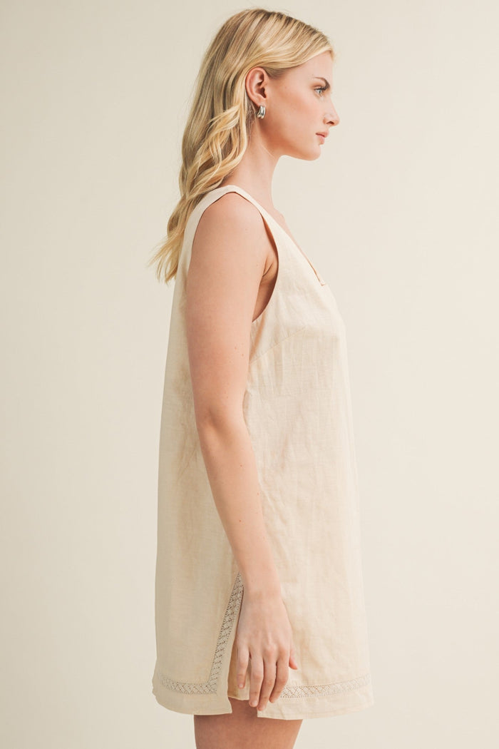 Cream sleeveless dress romper with lace trim at hemline, shown from side profile on model.