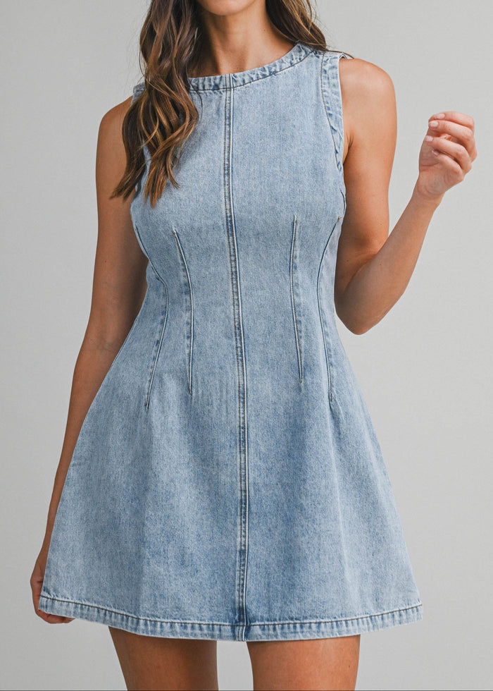 Woman wearing a light blue denim dress against a gray background