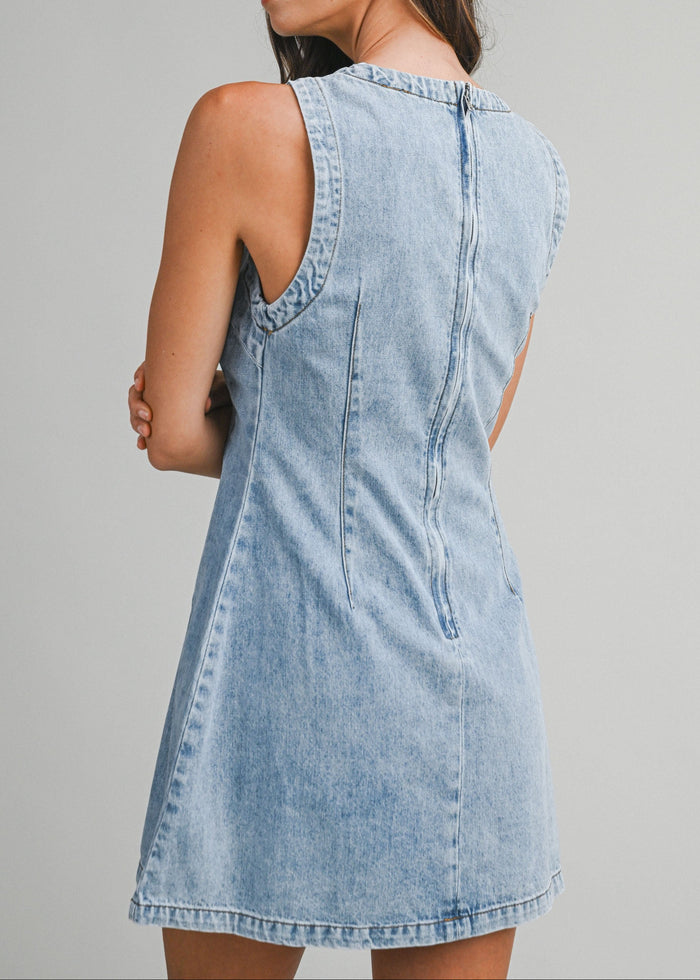 Woman wearing a light blue denim dress against a gray background