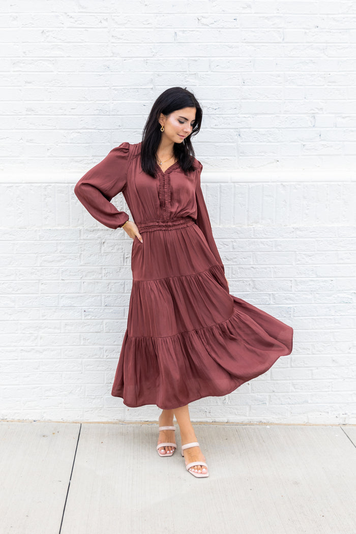 Burgundy maxi dress with long puffed sleeves, V-neckline, cinched waist, and tiered skirt.