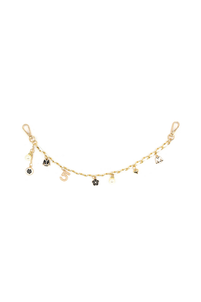 Gold-tone chain bag charm with lobster clasp ends and multiple hanging pendants including black enamel and metal charms.