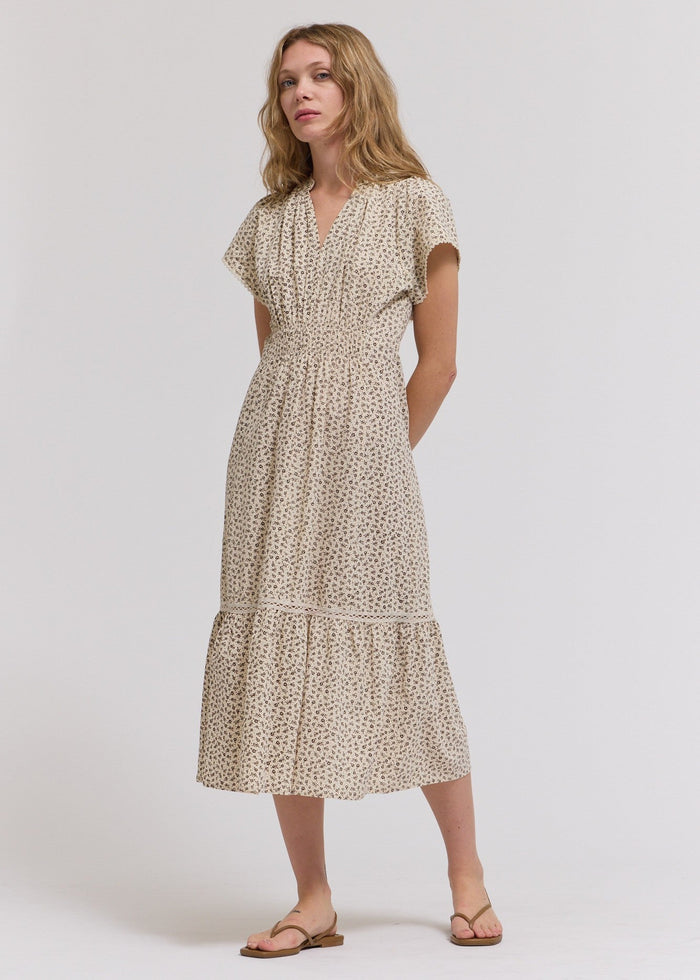 Beige midi dress with small floral print, short sleeves, V-neckline, and tiered skirt with pockets.