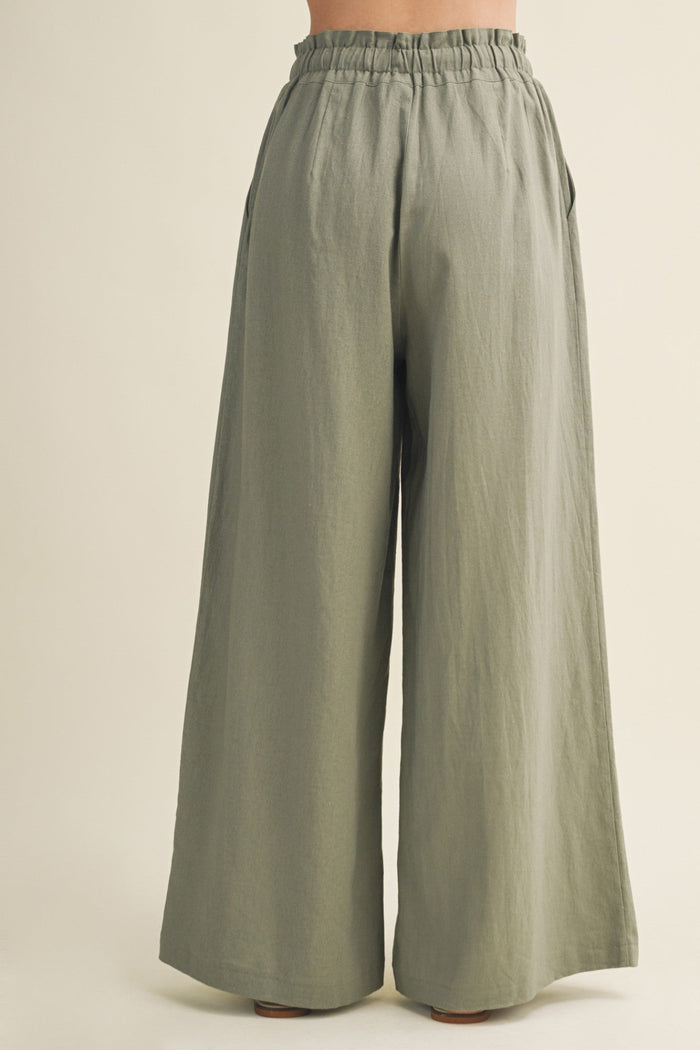 Sage green wide-leg pants with elastic waistband, shown from back view on model.