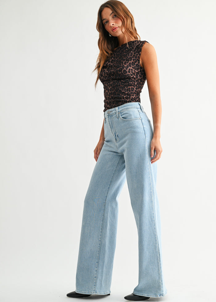 Woman wearing light blue wide-leg palazzo jeans with a black leopard print sleeveless top.