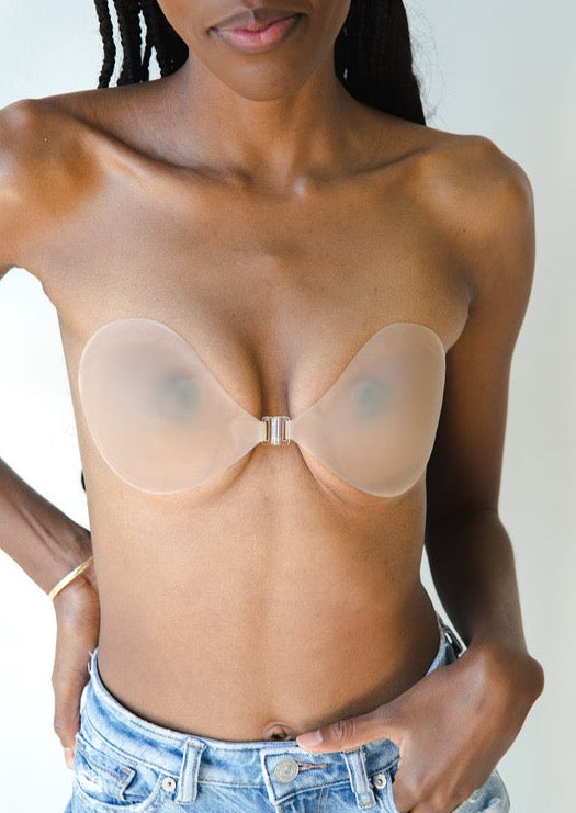 Nude adhesive bra with metallic center clasp worn on bare skin with denim jeans.