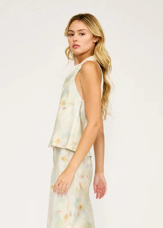 Cream sleeveless cowl neck top with watercolor floral print, shown on model from side angle.