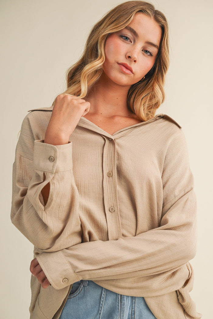 Beige ribbed button-down top with long sleeves and front pocket detail.