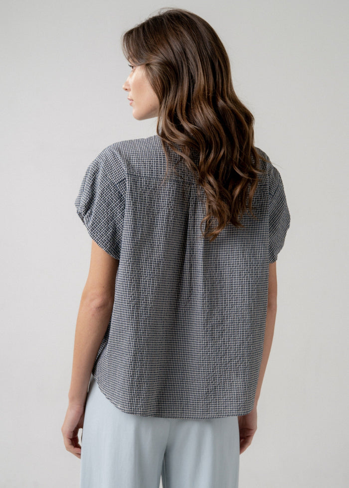 Gray and white checkered blouse with short puffed sleeves, shown from back on model wearing light gray pants.