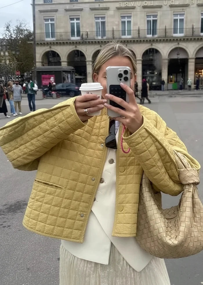 Yellow quilted jacket with button front and drop shoulders worn over cream layered top.